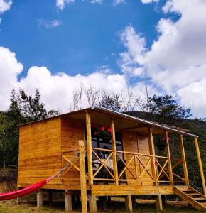 a wooden house with a red hammock in front of it at Cabaña Los Girasoles in Guatavita
