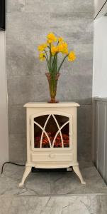eine Vase mit gelben Blumen auf einem weißen Schrank in der Unterkunft The Honeycomb in Ballyshannon