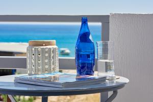 a table with a blue bottle and a glass at Muses Rooms Milos in Provatas