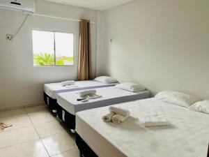 drei Betten in einem Zimmer mit Fenster in der Unterkunft Hotel Ondas do Mar in Salinópolis