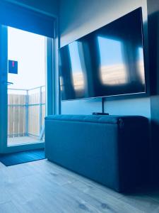 a living room with a blue couch and a flat screen tv at TB Penthhouse in Akureyri