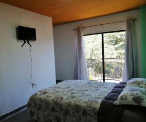 - une chambre avec un lit et une grande fenêtre dans l'établissement Hotel El Mirador, à Xilitla