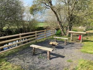 two wooden benches in front of a fence at Lakeside Lodge in Taunton