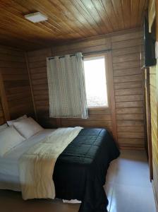 een slaapkamer met een bed in een kamer met een raam bij Chalés Schwambach in Domingos Martins