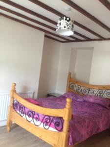 a bedroom with a wooden bed with purple sheets at Honeycomb Cottage in Aberdare