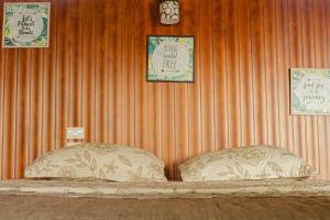 a bed with two pillows in a room with a wall at Corcovado Green Cabin in Drake