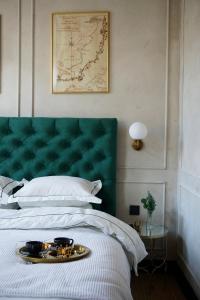 Una cama con un cabecero verde con una bandeja. en Modiste en Kuldīga