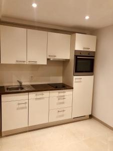 an empty kitchen with white cabinets and a microwave at Big Apartment with garden Rapperswil-Jona in Jona