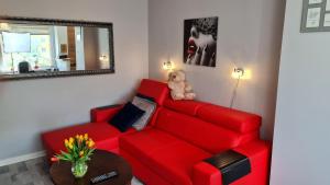 a teddy bear sitting on a red couch in a living room at Apartament z widokiem na las in Sopot