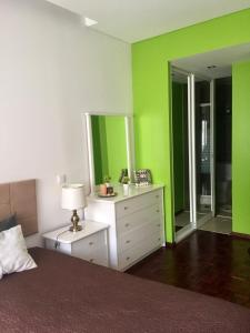 ナザレにあるNazaré - Avenida Vieira Guimarãesの緑の壁のベッドルーム1室、ベッド1台、ドレッサーが備わります。