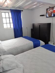 a bedroom with two beds and a tv on the wall at Club Recreativo Las Guitarras in Florián