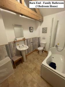 a bathroom with a tub and a sink and a toilet at Chestnut Farm Holiday Cottages in Matlock