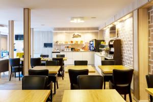 a restaurant with tables and chairs and a kitchen at BRIT Hotel Rouen Nord - Barentin in Barentin