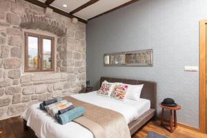 a bedroom with a bed and a stone wall at Kazerma Apartment in Perast
