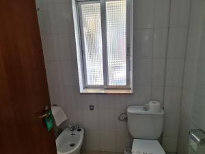 a bathroom with a toilet and a sink and a window at Hospedaxe Don Manuel in O Vicedo