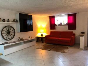 a living room with a red couch and a clock at Residence Ai Laghi in Temossi