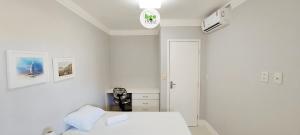a white bedroom with a bed and a clock on the wall at COSTE0100 - Residencial Luz das Acácias in Salvador +98 photos