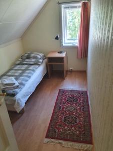 1 dormitorio con cama, mesa y alfombra en Sjarmerende feriehus i Olden rett ved fjorden, en Stryn