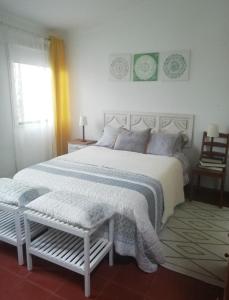 a bedroom with a large white bed and a window at Casinha Amarela in Sintra