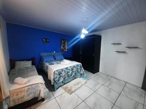 a bedroom with two beds and a blue wall at ACONCHEGO DE CANELA/RS in Canela