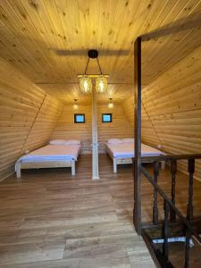 two beds in a wooden room with a chandelier at Pensiunea La Iepurasi in Lunga