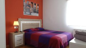 a bedroom with a bed with a striped bedspread and a lamp at Apartamento La Paz - Habitaciones con baño no compartido en pasillo in Oviedo