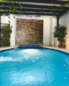 una gran piscina azul con una pared de ladrillo en Hotel La Estación, en San Juan del Sur