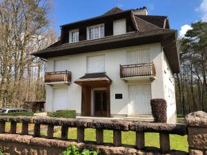 une maison blanche avec une clôture devant elle dans l'établissement Appartement bagnoles, à Bagnoles-de-l'Orne