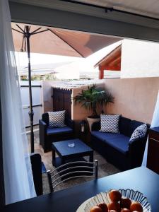 une terrasse avec des canapés, des tables et un parasol dans l'établissement Pavillon 4/6 pers. 30 m² Gruissan Les Ayguades, à Gruissan