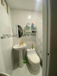 a white bathroom with a toilet and a sink at Salinas villa in La Libertad