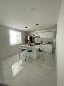 a white kitchen with chairs and a kitchen island at Salinas villa in La Libertad