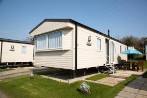 a small white house with a table and an umbrella at 51 Lytchett Bay View, 3 bed, Rockley Park Poole in Poole