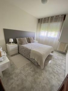 een witte slaapkamer met een bed en een raam bij Apartamento El Nogal 1 in Tui
