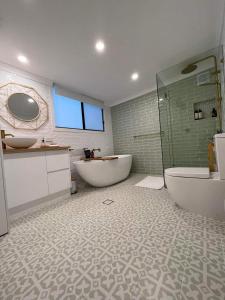 uma casa de banho com 2 lavatórios, uma banheira e um chuveiro em Maunder Cottage em Aldinga