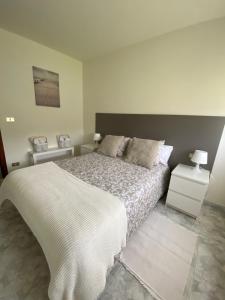 een witte slaapkamer met een bed en twee nachtkastjes bij Apartamento El Nogal 1 in Tui