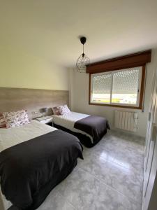 a bedroom with two beds and a window at Apartamento El Nogal 1 in Tui +1 photo