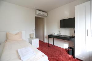 Dormitorio con cama, escritorio y TV en Mille Stelle Hotel en Eggenstein-Leopoldshafen