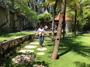 Akatara Hotel في نوسا بينيدا: a woman walking on a path in a garden