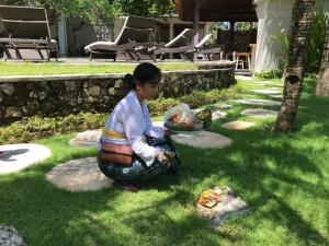 Akatara Hotel في نوسا بينيدا: فتاة صغيرة جالسة على العشب مع طائرة ورقية