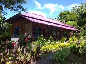 une petite maison avec un toit rouge dans un jardin dans l'établissement Leko Lembo Guesthouse, à Keli