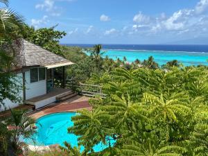 un complexe avec une piscine et l'océan dans l'établissement Moorea Happy Bungalow, à Teavaro