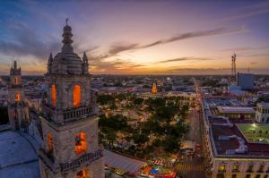 a clock tower in a city at sunset at HIT Merida Hotel Boutique in M&eacute;rida
