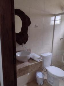 a bathroom with a sink and a toilet and a mirror at Armazém do Porto Chalé Ixora in Morretes