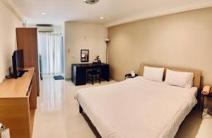 Schlafzimmer mit einem großen weißen Bett und einem Schreibtisch in der Unterkunft Grand Residence in Bangkok
