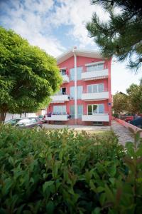 un edificio rosa di fronte a un parcheggio di Apartments Danijela 2 a Sukošan (San Cassiano)