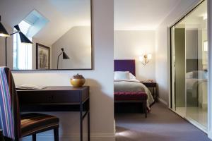a bedroom with a bed and a desk and a mirror at Old Parsonage Hotel in Oxford