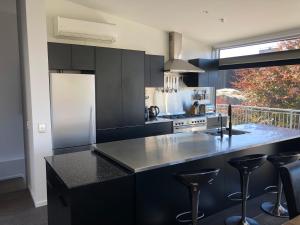 a kitchen with black cabinets and a counter with stools at Remarkable Escape for 8 in Queenstown