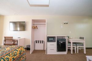 Habitación de hotel con cama, escritorio y mesa. en Regency Inn & Suites DFW, en Euless