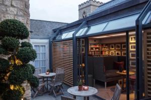 a garden room with a glass extension with a chair and tables at Old Parsonage Hotel in Oxford