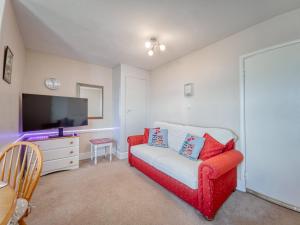 a living room with a red couch and a tv at Apartment 5 - 1 Bedroom Sea Front-Sea Views-Free Parking in Paignton